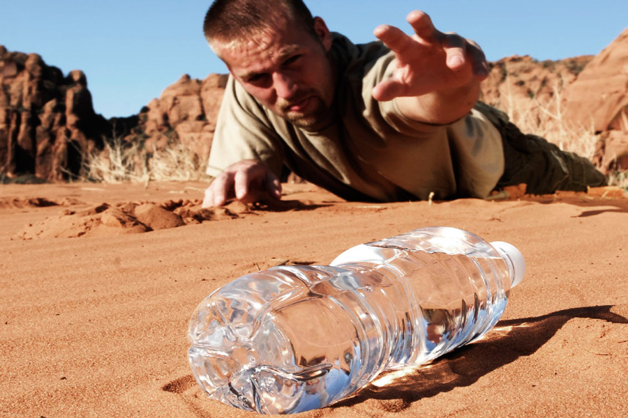 Мужчина в пустыне тянется за бутылкой воды. Аптечка туриста в Египте