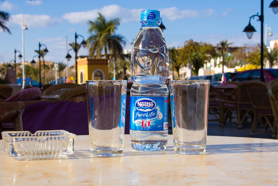 Бутылка воды и 2 стакана на столе на улице в Египте. Правила безопасности в Египте
