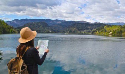 Туристка с картой смотрит на озеро