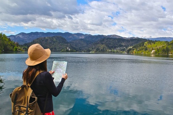 Туристка с картой смотрит на озеро