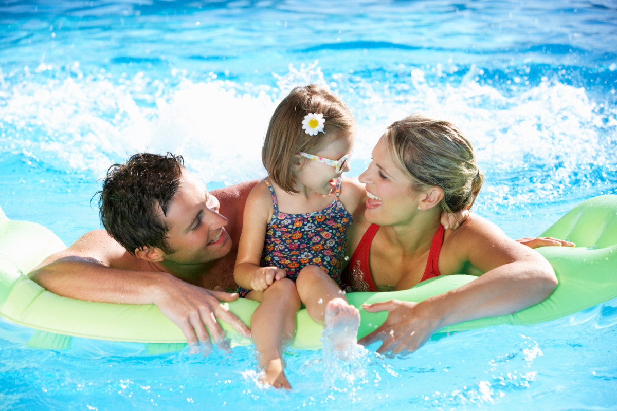 Мама и папа с ребенком девочкой на надувном круге в бассейне в Турции
