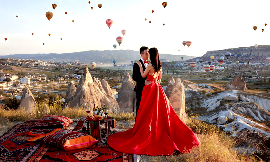 Молодая пара влюбленных на фоне воздушных шаров в Каппадокии. Отель Cappadocia Cave Resort & Spa 5*, Каппадокия, Турция