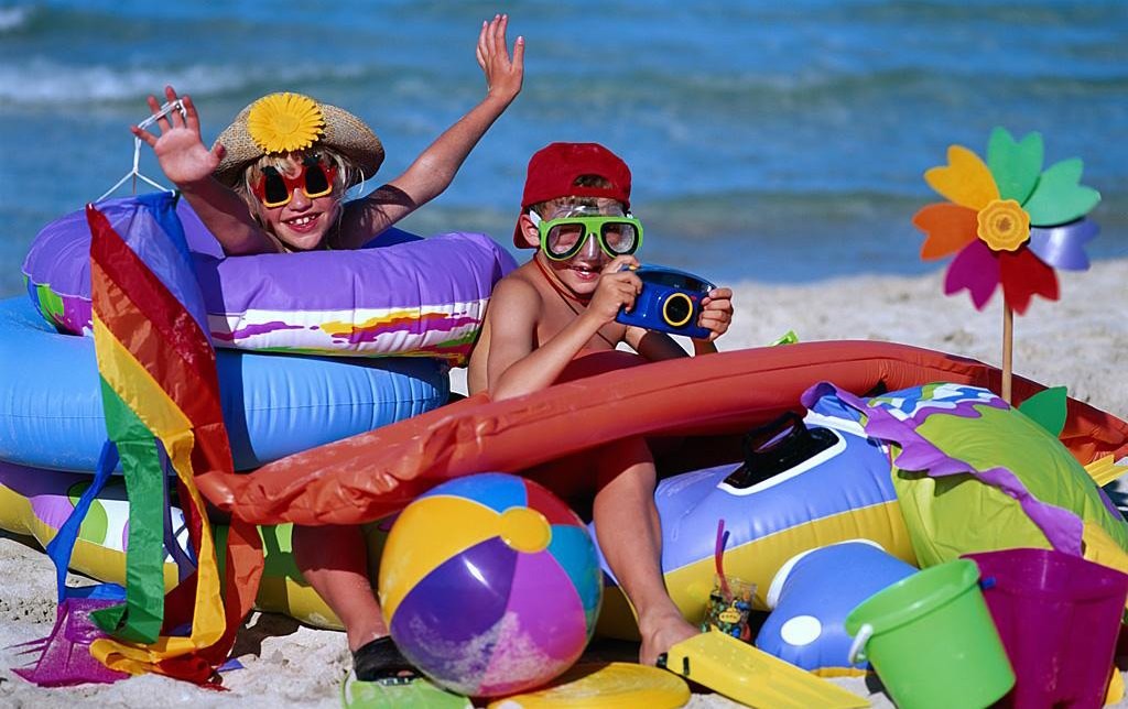Двое детей в надувных кругах, масках с трубкой и с мячами на берегу пляжа в Турции
