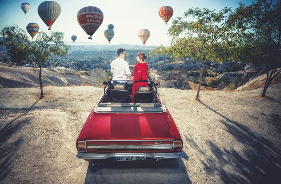 Пара в авто на фоне воздушных шаров в Каппадокии, Турция