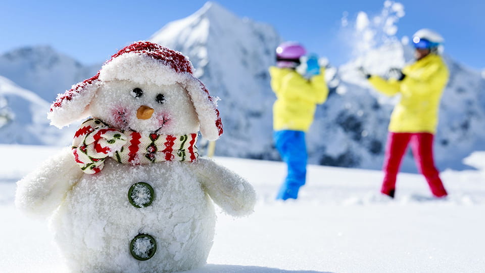 Снеговик и двое молодых людей играющих в снежки