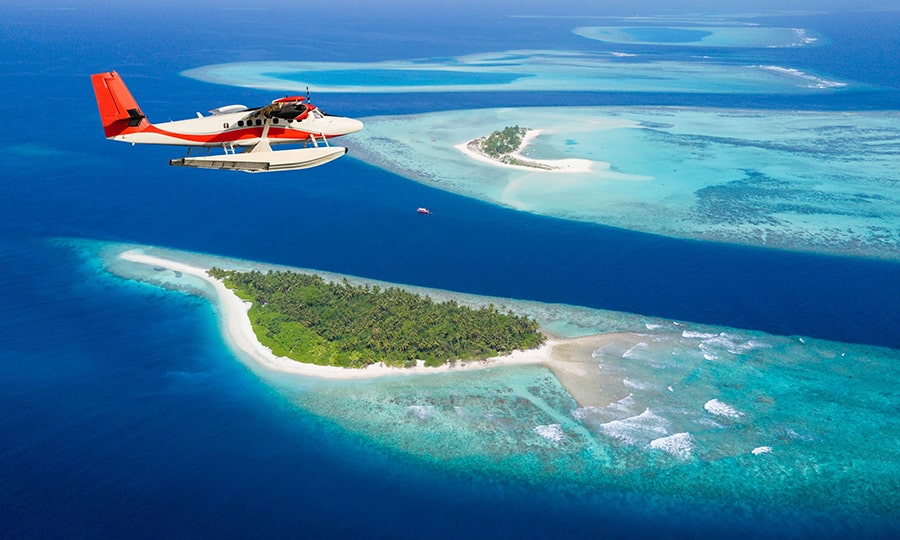 Одномоторный самолет летит над Мальдивами